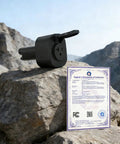 Black Essential Badass NACS V2L Adapter on rocky terrain with Supplier's Declaration of Conformity for camping and emergency use.