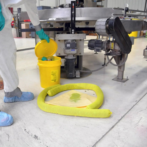 Worker using Hazmat Spill Kit in Reusable Bucket with 10 Yellow Pads, 3 Absorbent Socks, Nitrile Gloves, and Safety Goggles in industrial setting.