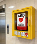 AED Sign Stickers, 2 Pack, 10x7 Large Vinyl Wall Signage For Quick AED Location, High Visibility Reflective Decals For Cabinets, Walls, Halls, And Emergency Response Areas. AED sticker on yellow cabinet beside elevator.