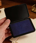 Hand holding a blue Dead Zero Smudge Fast Dry Pigment Ink Pad For Rubber Stamps and Official Signatures.