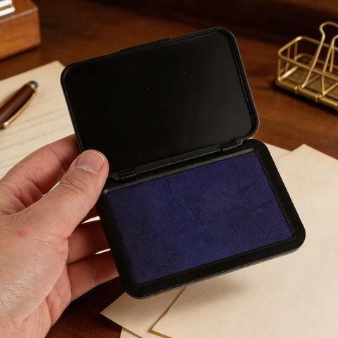 Hand holding a blue Dead Zero Smudge Fast Dry Pigment Ink Pad For Rubber Stamps and Official Signatures.