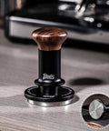 58mm Espresso Tamper With Ripple Base And Spring Loaded Precision Pressure For Even Extraction on countertop, walnut handle visible.