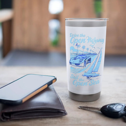 Road Trip Vibes Stainless Steel Insulated Tumbler With Open Highway Car And Open Sea Sail Design on table with lid
