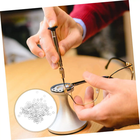 Person using Metal Eyeglass Frame Washers 200 Pcs Set for Rimless Glasses, Quick Fix Repair Accessories on a table.