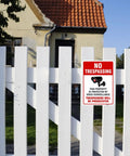Straight Up Legal Deterrent Video Surveillance And No Trespassing Signs 4 Pack Aluminum Security Plates mounted on wooden fence.