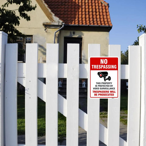 Straight Up Legal Deterrent Video Surveillance And No Trespassing Signs 4 Pack Aluminum Security Plates mounted on wooden fence.