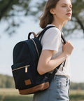 Person wearing a black backpack outdoors with gold zipper pull visible.