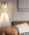 Crystal Bubble Wall Sconce LED Light In Nordic Gold Finish illuminating modern living room with glass bubble shade.