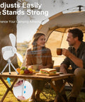 Portable Camping Fan With LED Lights And Remote, 9.25 Inch Wireless Rechargeable Tent Ceiling Fan With Timer, on a picnic table outdoors near a tent.
