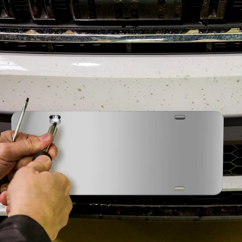 Person installing Stainless Steel License Plate Backing Twin Pack 12 By 6 Inches Silver Car Tag Holder With Screws And Caps on car front