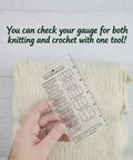 Hand holding Super Crisp Acrylic Gauge Ruler For Knitting And Crochet No Sweat Stitch Measurement Guide With Transparent Grid over textured knit fabric.