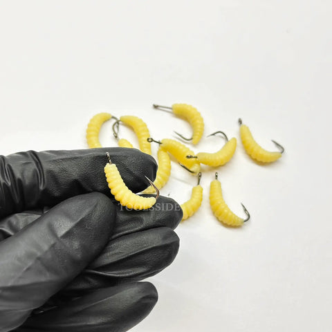 Gloved hand holding a soft yellow worm from Rugged Rubber Maggots Bait Set For Freshwater Fishing With 12 Hooks And 12 Worms Crappie
