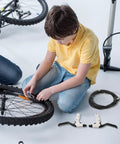 Child installing Score Beast Mode Stopping Power With This Lightweight Mechanical Disc Brake Set with aluminum calipers on a bike wheel.