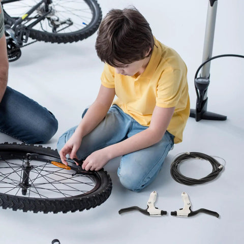 Child installing Score Beast Mode Stopping Power With This Lightweight Mechanical Disc Brake Set with aluminum calipers on a bike wheel.