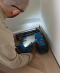 Gutsy 18 Volt Brushless Cordless Brad Nailer Kicks Out 2,000 Nails Per Charge used for trim installation in low light.