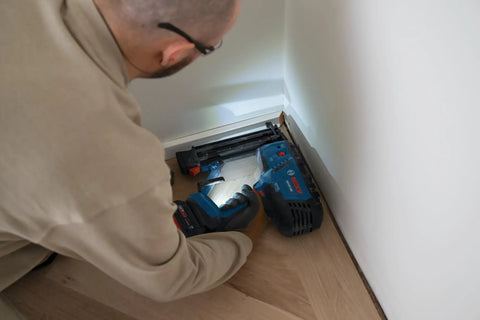 Gutsy 18 Volt Brushless Cordless Brad Nailer Kicks Out 2,000 Nails Per Charge used for trim installation in low light.
