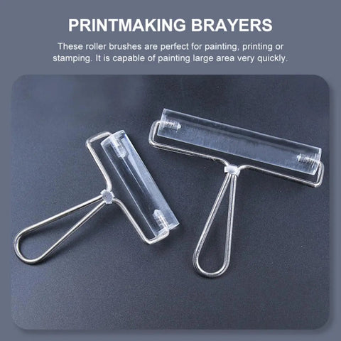 Heavy Duty Stainless Steel Paint Roller Set Two Piece Smooth Glide Action For Fast Canvas Coverage And Killer Oil Acrylic Finishes Game Changing Printmaking Essential - pair of clear roller brushes on dark surface.