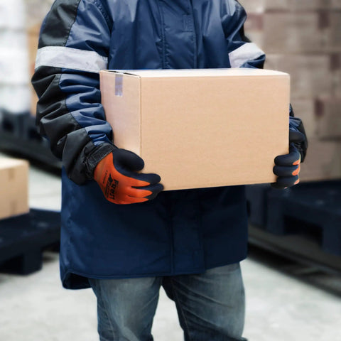 Person wearing waterproof insulated work gloves with thermal liner for cold weather handling a cardboard box in a freezer.