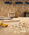 Built Like A Tank Brass Router Bushing Guide Set With 11 Sturdy Pieces arranged on a woodworking bench for precision routing tasks.
