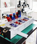 Rock Solid Electric Plastic Hot Bender And Acrylic Bending Press With Adjustable Heat Settings And Fast Chill Water Cooling For Perfect Pvc Angles And Knockout Storefront Displays on a work table with colored acrylic sheets.