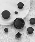 Round Black Plastic Hole Plugs Kit, 180 Pcs Self-Locking Panel Knockout Plugs for Kitchen Cabinets displayed on marble surface.