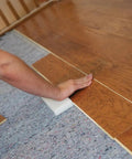 Pro Grade Flooring Underlayment Roll For Laminate Wood And Tile Sound Dampening Padding Compression Resistant Mat For Floating Glue Down Install Covers One Hundred Square Feet No Fuss Vibe Blocker Home Crew Staple being installed under laminate flooring.