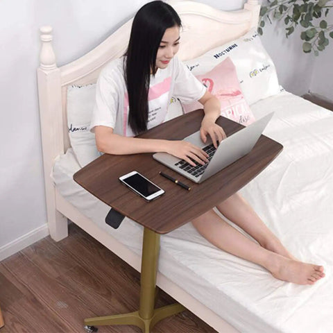 Rock Solid Mobile Laptop Desk With Fully Adjustable Rolling Casters Top Tier Portable Workstation in use beside a bed.