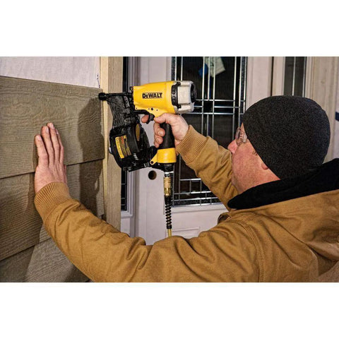Person using Pneumatic Coil Siding Nailer With Tool Free Adjustable Exhaust for fencing and siding projects on a wall.