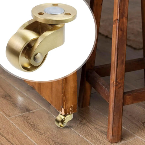 Badass Solid Brass Swivel Casters For Floor Mats Set Of 4, detailed view of polished caster wheel on wooden furniture leg.
