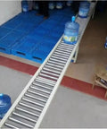 Extra Long Portable Conveyor For Docks And Trucks With Folding Rollers transporting water bottles on galvanized rollers.