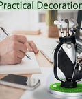 Mini Golf Pen Holder Desk Accessory Set With 3 Golf Club Pens And Ball On A Mini Putting Green Base next to a person writing.