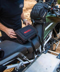Person placing Adventure Motorcycle Tool Kit 40 Piece Compact Tool Roll for Dual Sport and Adventure Bikes on a motorcycle seat.