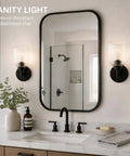 AOIOUR 10.4" 1‑Light Farmhouse Vanity Wall Sconce, Ribbed Glass Matte Black next to a mirror and sink in a bathroom.