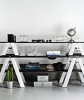 Minimalist three-tier white shelving with decor items against a plain wall.