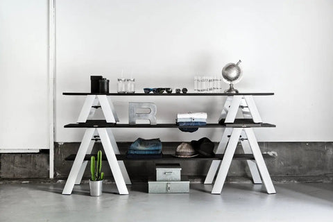 Minimalist three-tier white shelving with decor items against a plain wall.