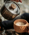 Kuksa Wooden Cup Handcarved 8 Oz Coffee Mug With Lanyard And Carabiner held while pouring from kettle