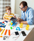 4-In-1 Solar Robot Kit For Kids Ages 8-12, STEM Toys For Boys And Girls, Solar Powered Fan Car And Robot, Pulley Powered Tank, Hands-On Electricity, Mechanics And Engineering Projects For Real World Learning on table with boy and man