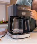 CafeCraft 12 Cup Programmable Coffee Maker With Stainless Steel Drip Design on kitchen counter being programmed.