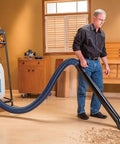 Hardcore 4 Inch Antistatic Dust Collection Hose With A Flexible Helix Ten Foot Layout, used for efficient sawdust extraction in a workshop.