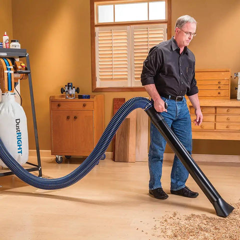 Hardcore 4 Inch Antistatic Dust Collection Hose With A Flexible Helix Ten Foot Layout, used for efficient sawdust extraction in a workshop.