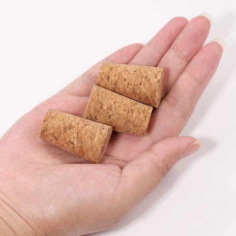 Hand holding three 25 Pack Natural Soft Wood Corks, Tapered Bottle Stoppers For Wine Making And DIY Crafts, Leakproof, Reusable