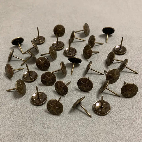 Hardcore Upholstery Tacks And Furniture Nails 100 Pack Heavy Duty Decorative Hardware Big Time Upgrade For DIY Restorations Solid Antique Brass, shown from angled view.