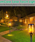 Outdoor scene with 43 Inch Solar Flameless LED Torches With Flickering Flame Effect lighting a garden path at night.