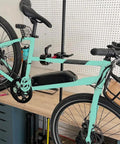 Portable Bike Repair Stand For On The Go Maintenance, Compact Space Saving Clamp Stand holding mint green bike in workshop