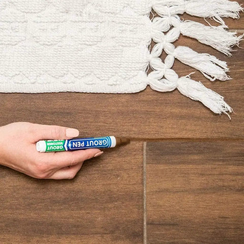 Hand using Brown Grout Pen Tile Paint Marker Waterproof Grout Colorant and Sealer Pen with Narrow 5mm Tip 7ml on tile floor