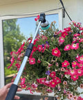 Extendable Garden Hose Wand With 28 To 36 Inch Reach Ten Spray Settings watering pink flowers in hanging basket outside