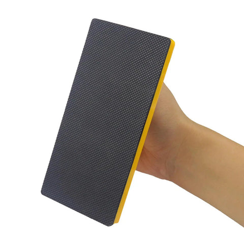Close-up of hand holding a Two Pack Safety Push Block Set With High Visibility No Slip Grip for woodworking, showing textured grip surface.