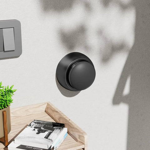 Heavy Duty Aluminum Door Stopper With Soft Silicone Head And Spring Shock Absorption Real Deal Wall Protector Rustproof Anti Scuff Door Holder In Sleek Black mounted on wall next to books.