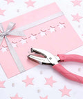 Pink star hole puncher next to decorated cardstock; Two Pack Handheld Heart And Star Shape Hole Punches With Ergonomic Soft Grip, 5mm Star And 5.5mm Heart Puncher For Paper Crafts, Scrapbooking, Tags, Tickets, DIY Projects, Pink And Green.