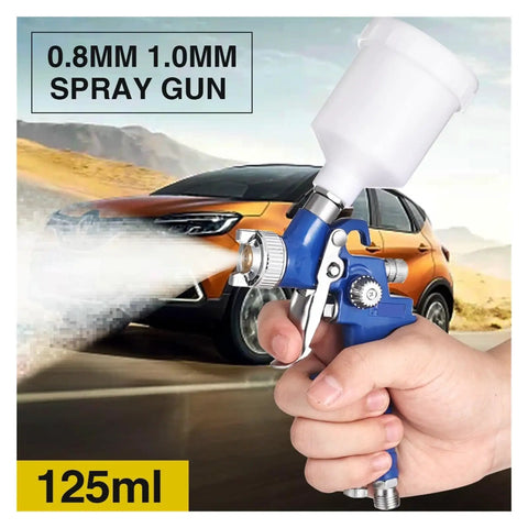 Pro Level Pneumatic Paint Spray Gun With One Millimeter Nozzle in hand spraying a mist, showing the clear fluid jar and controls.